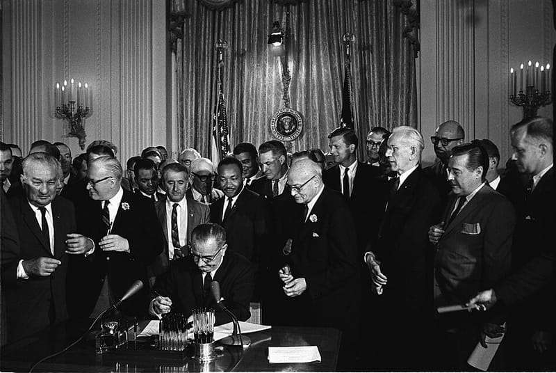 President Lyndon Johnson signing the Civil Rights Act of 1964, surrounded by onlookers
